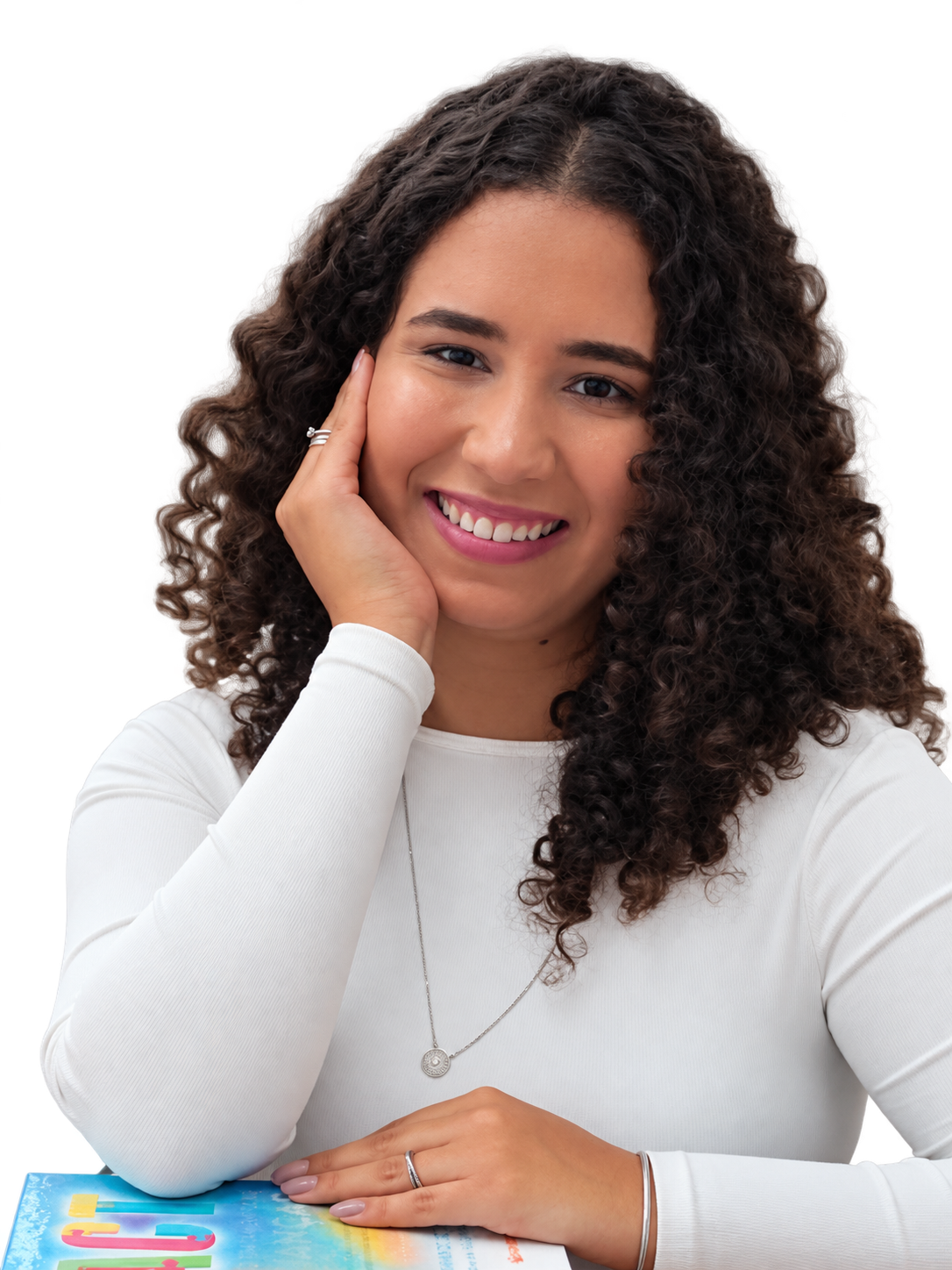 Mariana Magalhães sorrindo, apoiada em livros sobre terapia infantil
